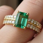 Colombian emerald wedding band with warm pure green center stone in yellow gold setting with diamond accents