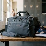 A modern gym bag with sneakers peeking out of a side compartment.